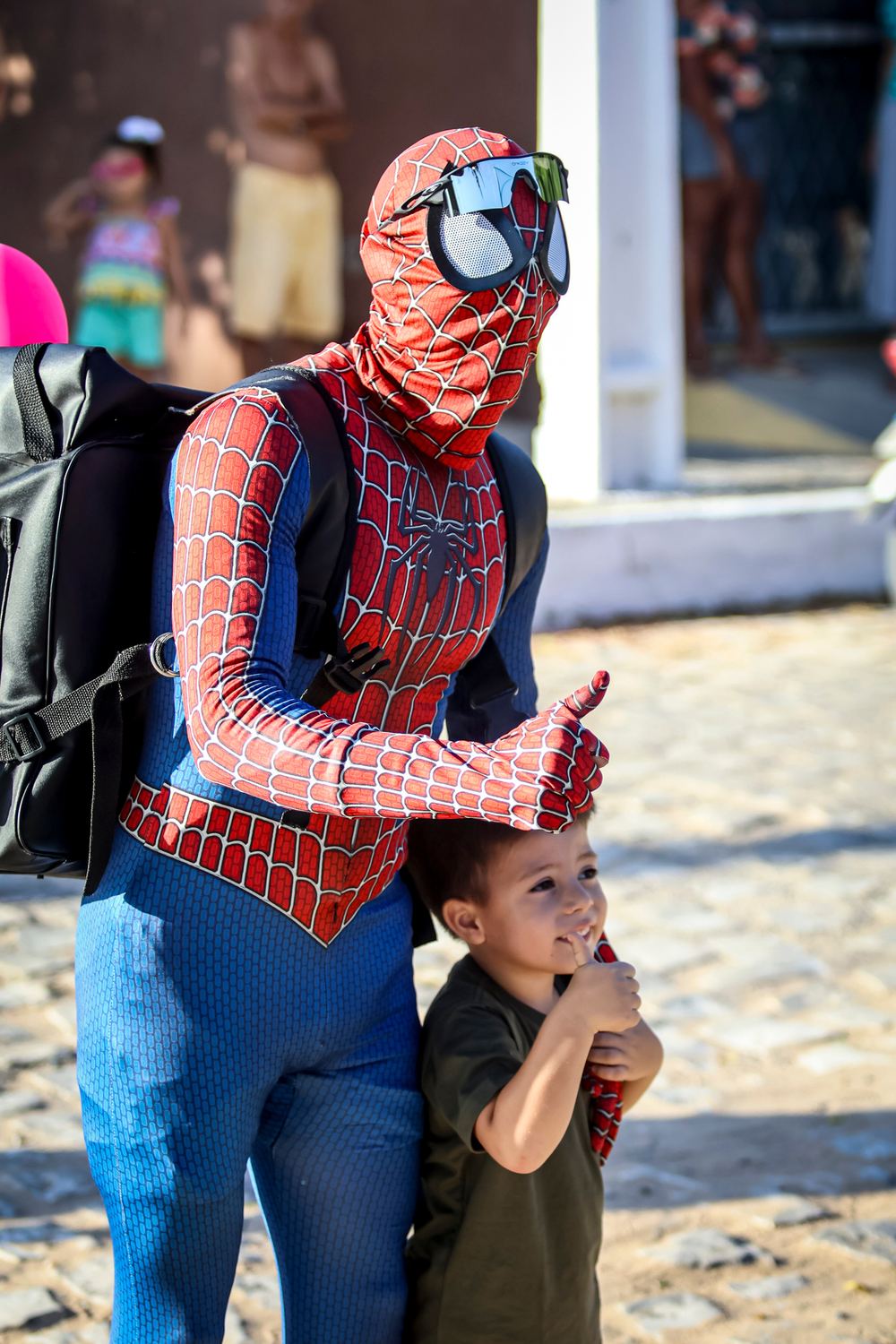 Voluntário fantasiado de Homem-Aranha abraçando uma criança