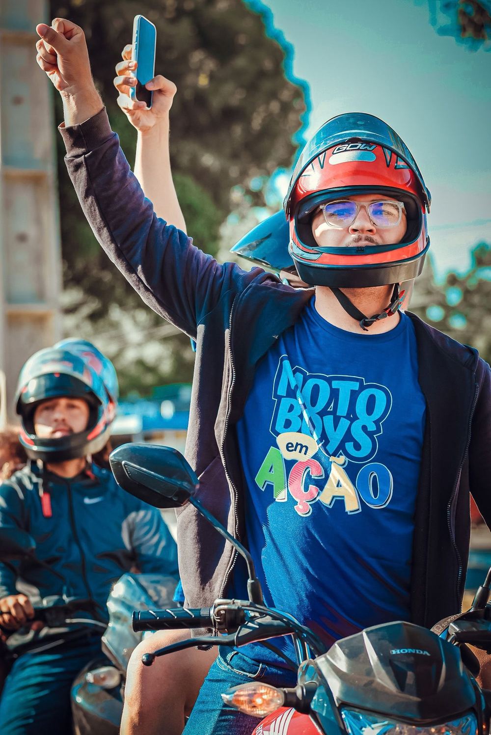 Motoboy de capacete comemorando com o braço erguido, camiseta Motoboys em Ação